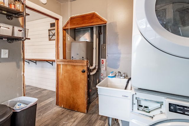 washroom featuring estacked washer and dryer, wood finished floors, and gas water heater