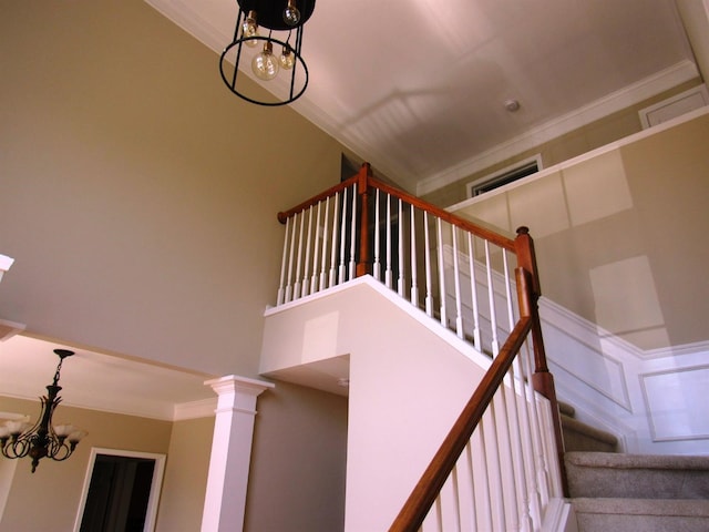 staircase featuring crown molding, a high ceiling, and a chandelier