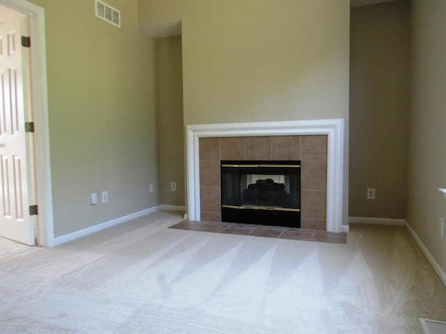 unfurnished living room with a tile fireplace, visible vents, and carpet floors