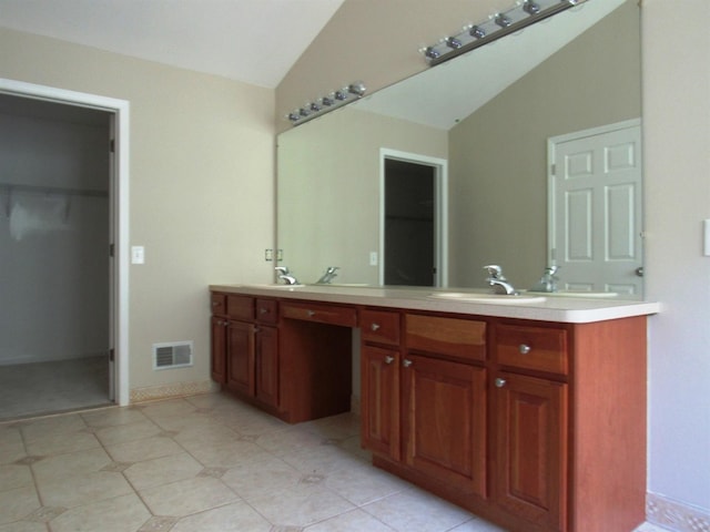 bathroom with lofted ceiling, visible vents, a sink, double vanity, and a spacious closet