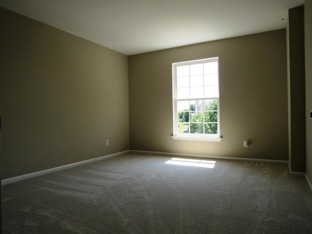 carpeted spare room featuring baseboards and visible vents