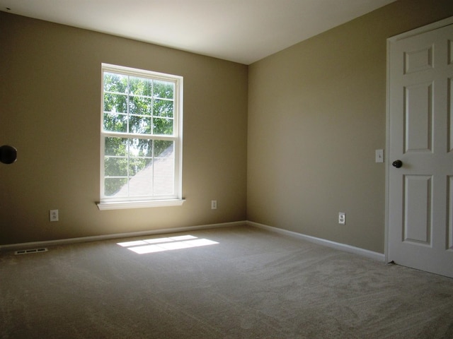 carpeted spare room with visible vents and baseboards