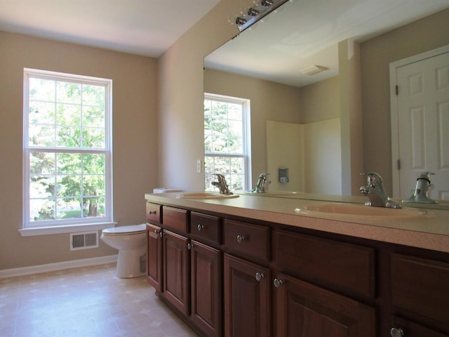 full bath featuring toilet, visible vents, baseboards, and a sink
