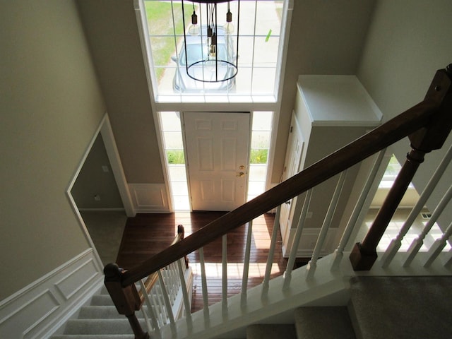 foyer entrance featuring a wainscoted wall, stairs, a decorative wall, and a towering ceiling