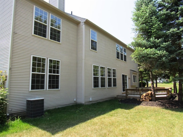 rear view of property featuring a yard, central air condition unit, a wooden deck, and a chimney