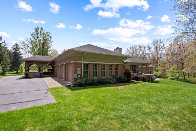 230 Corrie Rd, Ann Arbor, MI 48105 - rear view of property with an attached garage, a yard, brick siding, driveway, and a chimney