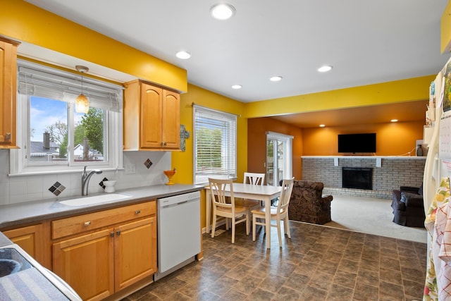 kitchen with white dishwasher, a sink, a fireplace, recessed lighting, and tasteful backsplash