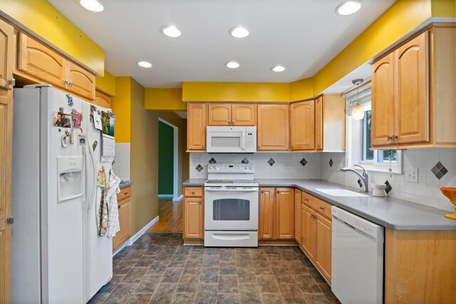 kitchen with white appliances, a sink, tasteful backsplash, stone finish floors, and baseboards