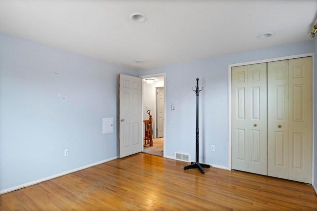 unfurnished bedroom with wood finished floors, baseboards, and a closet