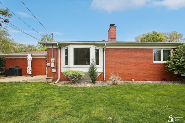 2330 Ashby St, Trenton, MI 48183 - view of front facade featuring a chimney, a front lawn, brick siding, and a patio