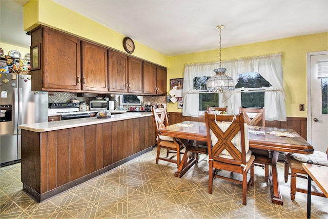 dining space with light floors, a wainscoted wall, and wood walls