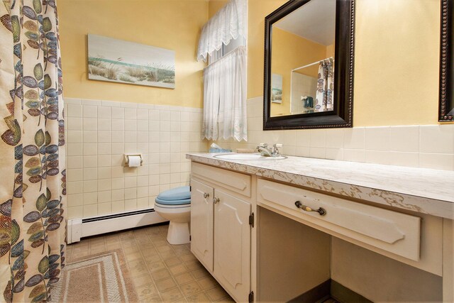 bathroom featuring a baseboard radiator, toilet, vanity, tile walls, and a wainscoted wall