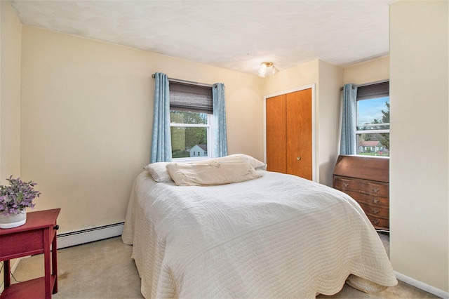 bedroom featuring a baseboard heating unit, light carpet, a closet, and baseboards