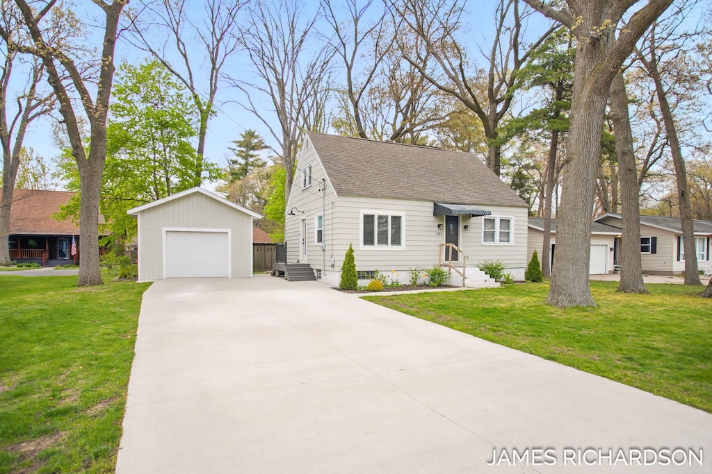 701 River St, Spring Lake, MI 49456 - view of front of property featuring driveway, an outbuilding, a garage, and a front lawn