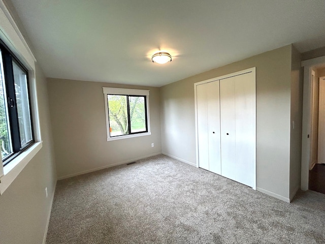 unfurnished bedroom with carpet, baseboards, and a closet