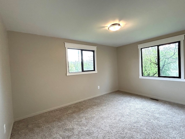 carpeted empty room with plenty of natural light and baseboards