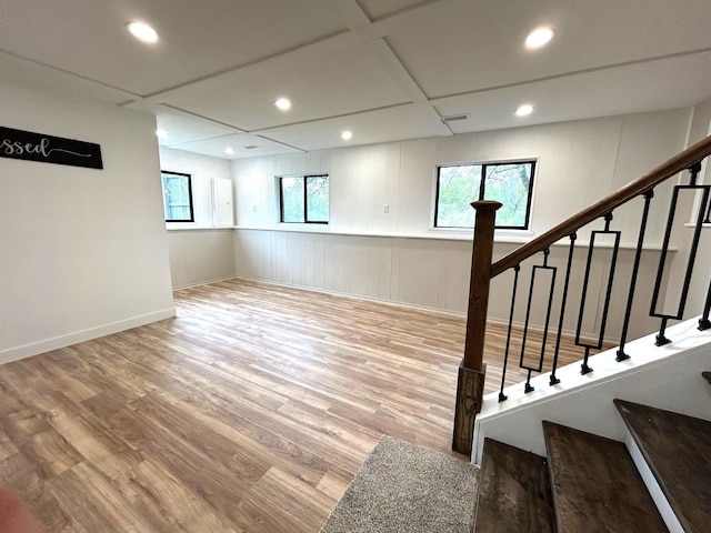 below grade area featuring recessed lighting, wood finished floors, stairs, a decorative wall, and baseboards