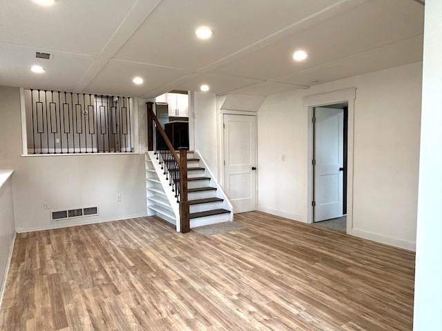 finished below grade area featuring stairway, recessed lighting, light wood finished floors, and baseboards