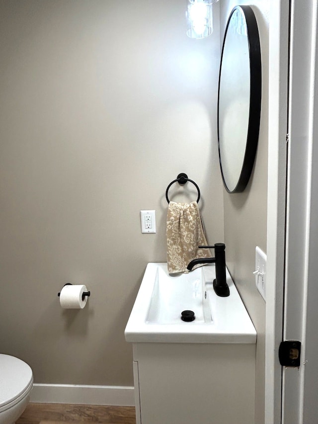 bathroom featuring baseboards, vanity, toilet, and wood finished floors