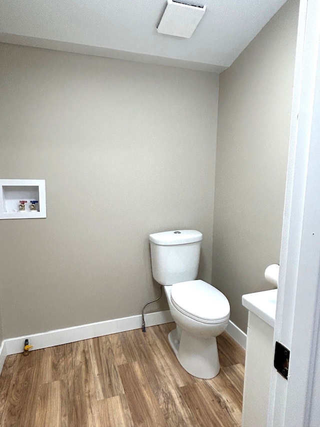 bathroom with wood finished floors, toilet, baseboards, and vanity