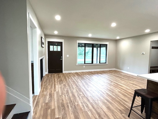 foyer featuring light wood-style flooring, recessed lighting, baseboards, and a fireplace