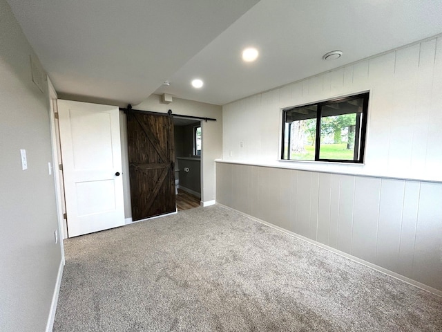 carpeted spare room featuring a barn door, baseboards, and recessed lighting
