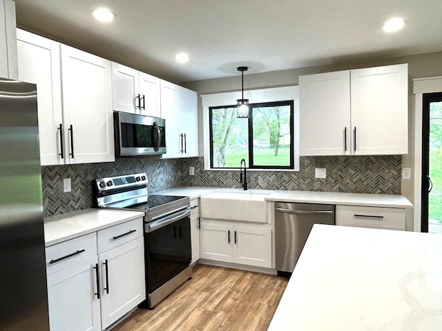 kitchen featuring stainless steel appliances, a sink, light wood-style flooring, white cabinets, and recessed lighting
