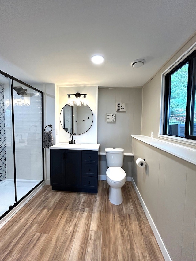 full bath featuring wood finished floors, a stall shower, toilet, vanity, and baseboards