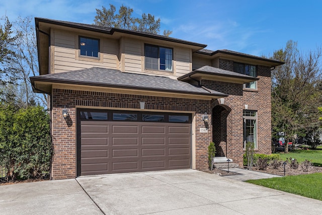 prairie-style home with brick siding, driveway, a garage, and a shingled roof