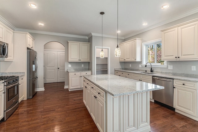 kitchen with appliances with stainless steel finishes, a sink, dark wood-type flooring, light stone counters, and hanging light fixtures