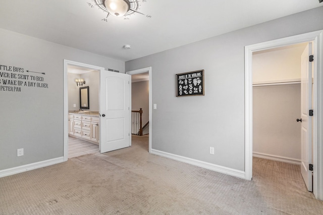 unfurnished bedroom with a spacious closet, light colored carpet, baseboards, and a closet