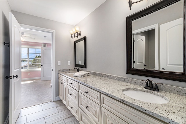 bathroom with double vanity, ceiling fan, and baseboards