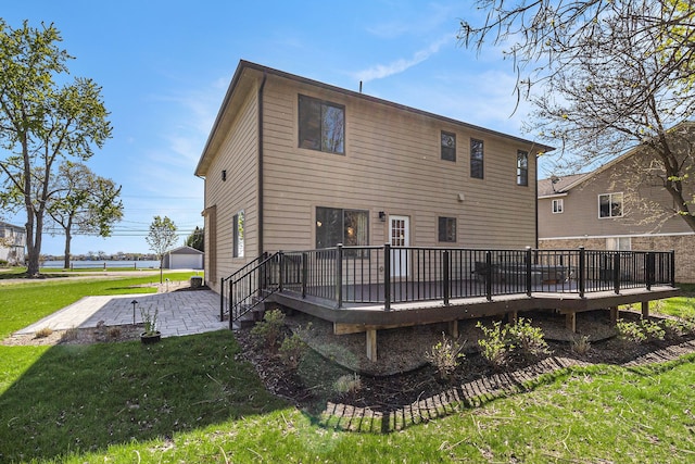 back of house with a wooden deck, a lawn, and a patio