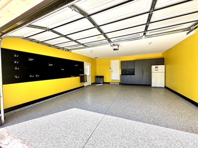 garage with freestanding refrigerator, baseboards, and a garage door opener