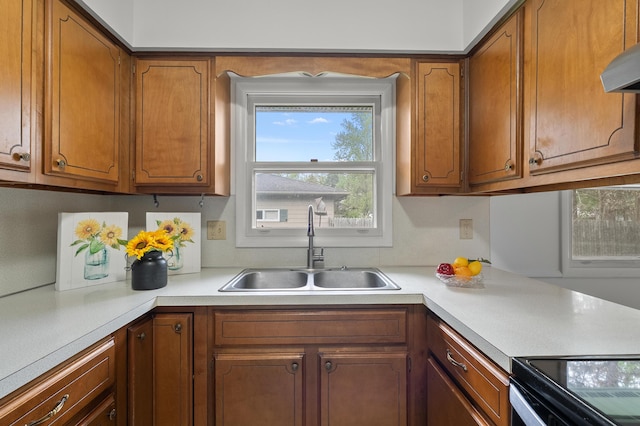 kitchen featuring a sink, light countertops, brown cabinetry, and extractor fan