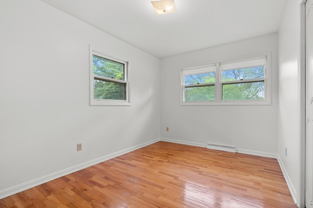 spare room with healthy amount of natural light, light wood-style floors, and baseboards