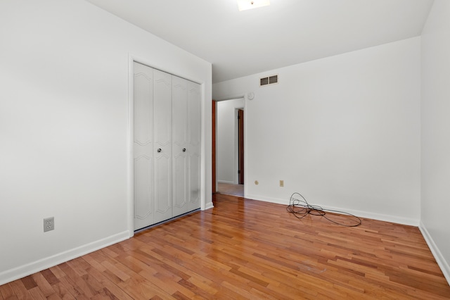 unfurnished bedroom with light wood-type flooring, baseboards, and a closet