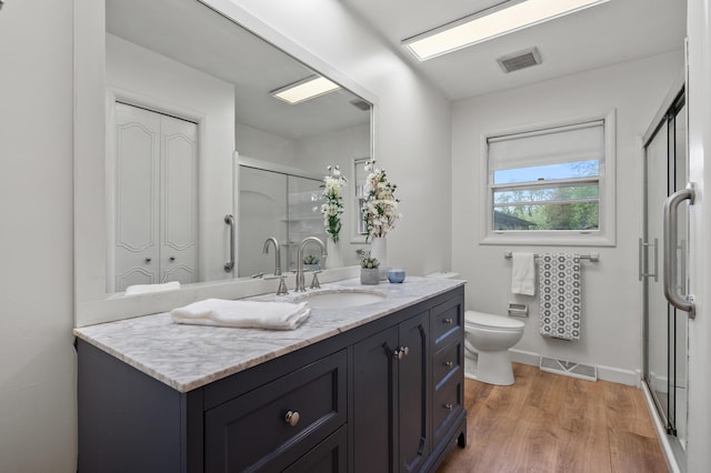bathroom with a shower stall, vanity, wood finished floors, toilet, and baseboards