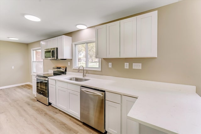 2365 Middlebelt Rd, West Bloomfield, MI 48324 - kitchen featuring stainless steel appliances, a sink, light wood finished floors, light countertops, and white cabinetry