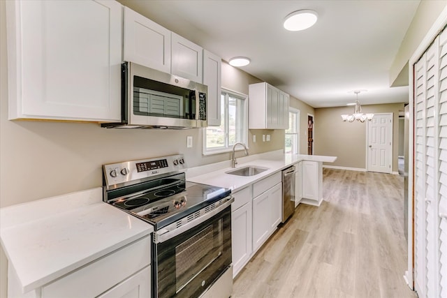 2365 Middlebelt Rd, West Bloomfield, MI 48324 - kitchen with stainless steel appliances, a sink, a chandelier, white cabinets, and light countertops