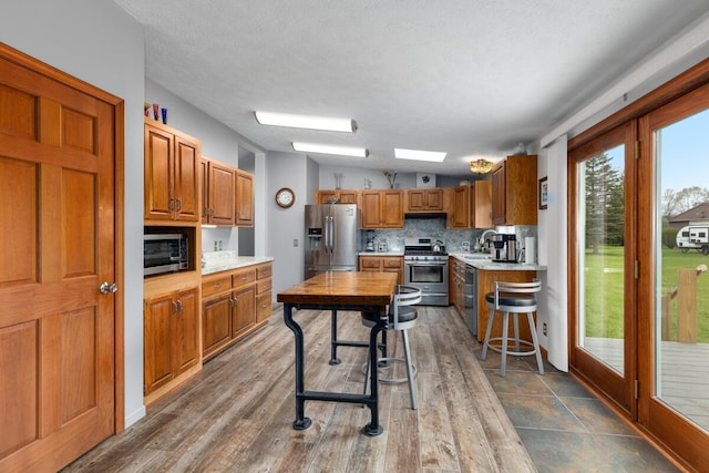 880 W Ave, Big Rapids, MI 49307 - kitchen featuring stainless steel appliances, a sink, light countertops, brown cabinets, and tasteful backsplash