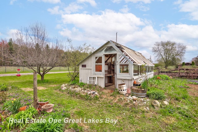 rear view of property with a greenhouse, an outbuilding, and a yard