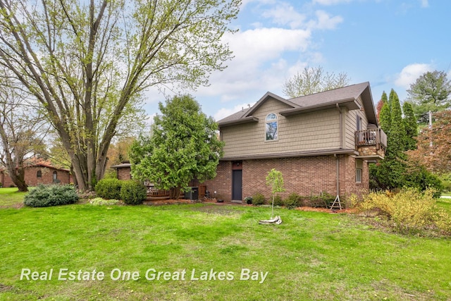 view of front of home featuring a balcony, a front yard, brick siding, and a wooden deck