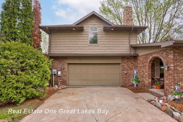 view of front of property with concrete driveway, an attached garage, brick siding, and a chimney