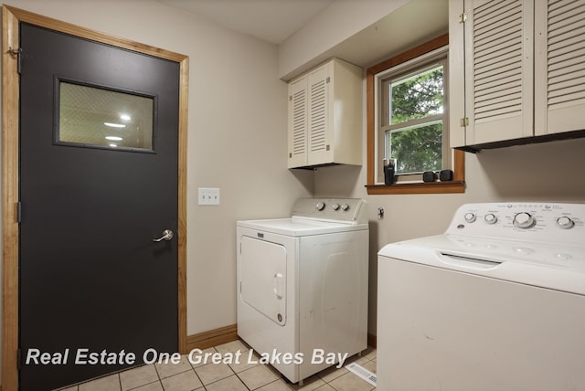 washroom with washing machine and clothes dryer, baseboards, light tile patterned floors, and cabinet space