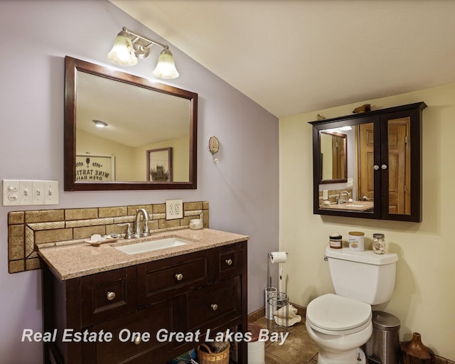 bathroom with toilet, tasteful backsplash, tile patterned flooring, vanity, and baseboards