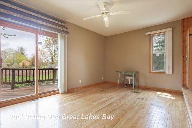 unfurnished room with wood-type flooring, a ceiling fan, and baseboards