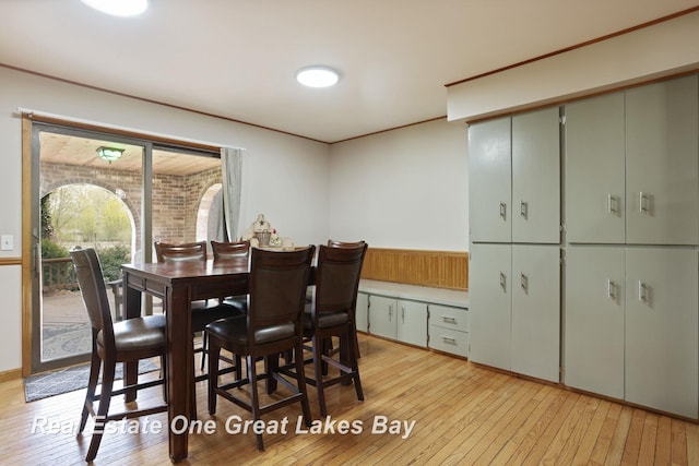 dining room with light wood-type flooring and wainscoting