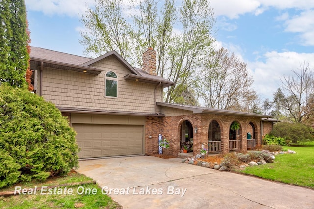 view of front facade with covered porch, a chimney, concrete driveway, an attached garage, and brick siding