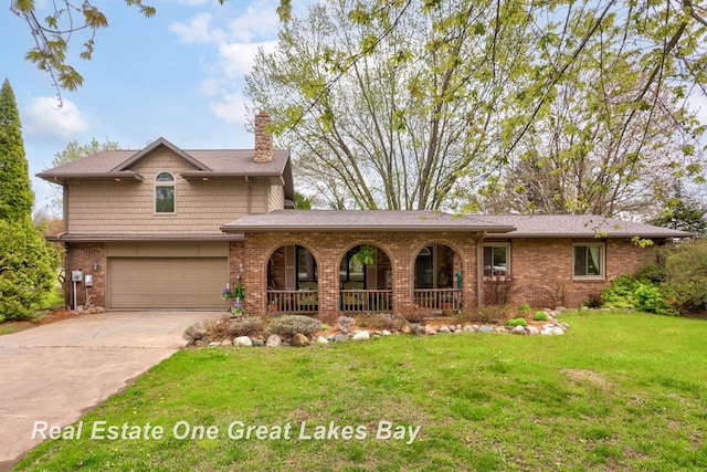 traditional-style home with covered porch, a chimney, a garage, concrete driveway, and a front yard